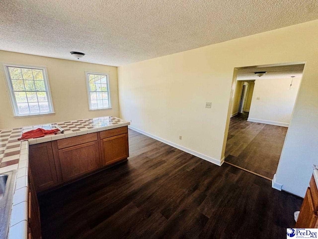 interior space with a textured ceiling, baseboards, and dark wood finished floors