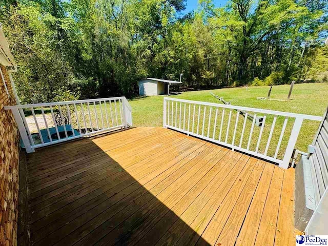 deck with an outbuilding, a lawn, and a storage unit
