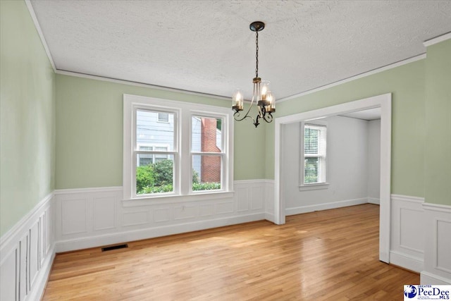 312 Greene St, Cheraw, SC 29520 - unfurnished dining area with a chandelier, wainscoting, ornamental molding, light wood-style flooring, and a textured ceiling