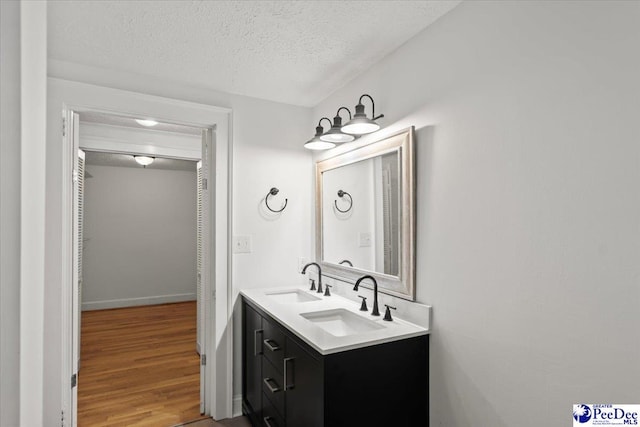 312 Greene St, Cheraw, SC 29520 - bathroom featuring a textured ceiling, double vanity, and wood finished floors