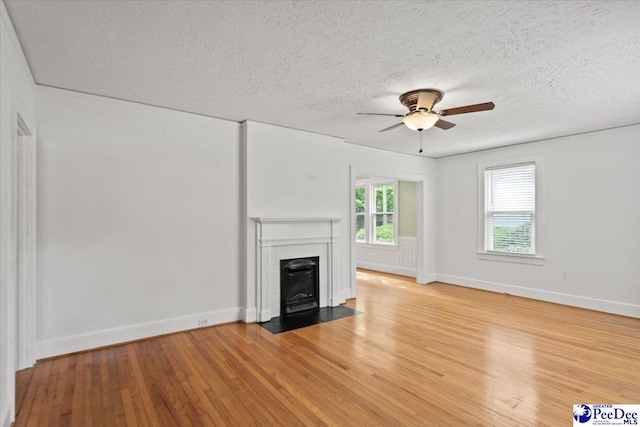 312 Greene St, Cheraw, SC 29520 - unfurnished living room with ceiling fan, a fireplace with flush hearth, light wood-style floors, a textured ceiling, and baseboards