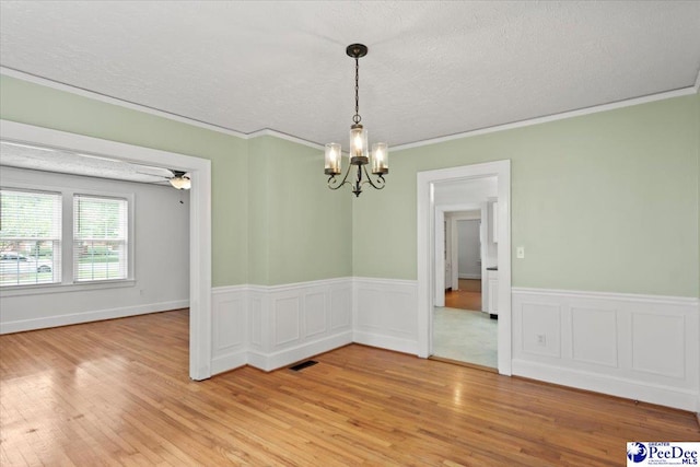 312 Greene St, Cheraw, SC 29520 - unfurnished dining area featuring a chandelier, light wood finished floors, a textured ceiling, ornamental molding, and a wainscoted wall