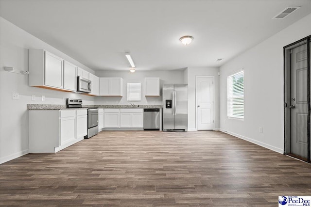 3229 Winding Way Dr, Florence, SC 29506 - kitchen with stainless steel appliances, dark wood finished floors, white cabinets, baseboards, and a sink