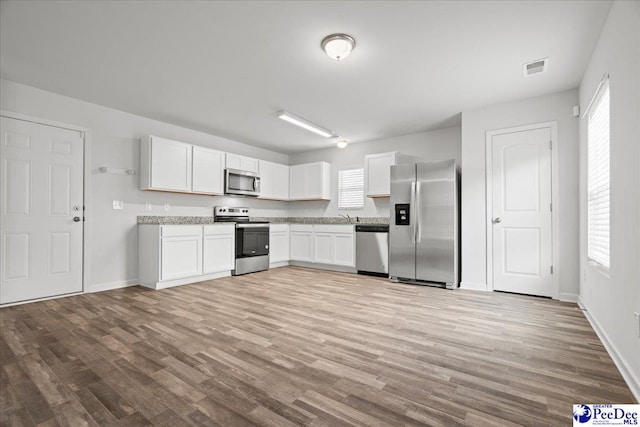 3229 Winding Way Dr, Florence, SC 29506 - kitchen featuring appliances with stainless steel finishes, white cabinetry, wood finished floors, and baseboards