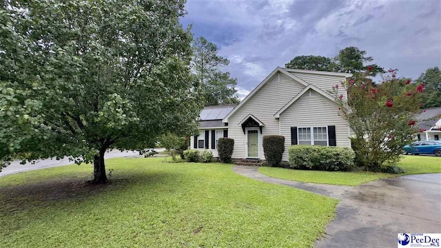 view of front of home with a front yard and solar panels