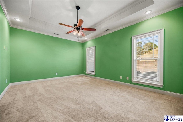 empty room featuring ceiling fan, ornamental molding, a tray ceiling, and light carpet