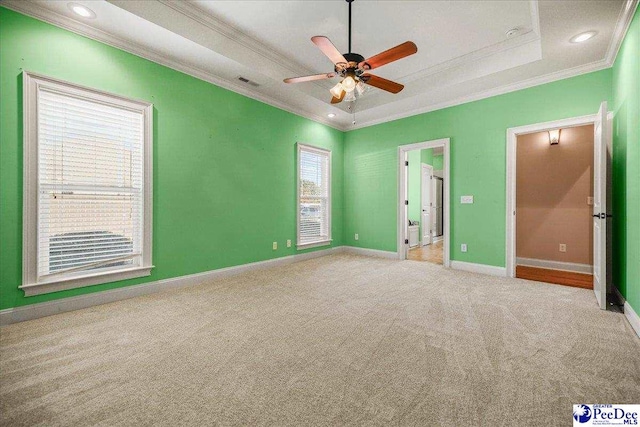 unfurnished bedroom featuring crown molding, light carpet, ceiling fan, and a tray ceiling