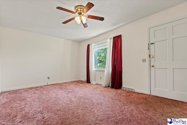 carpeted empty room with a textured ceiling, visible vents, baseboards, and a ceiling fan