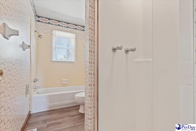 full bathroom featuring toilet, washtub / shower combination, wallpapered walls, and wood finished floors