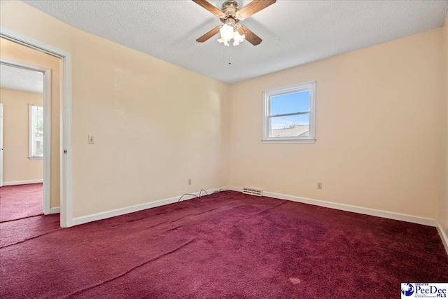 unfurnished room with ceiling fan, dark colored carpet, and visible vents