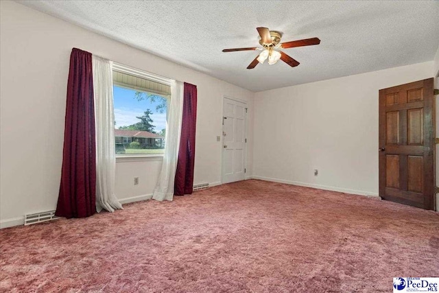 unfurnished room with a textured ceiling, carpet flooring, a ceiling fan, and visible vents