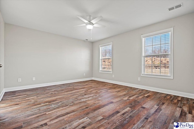 unfurnished room with baseboards, visible vents, ceiling fan, and dark wood-type flooring