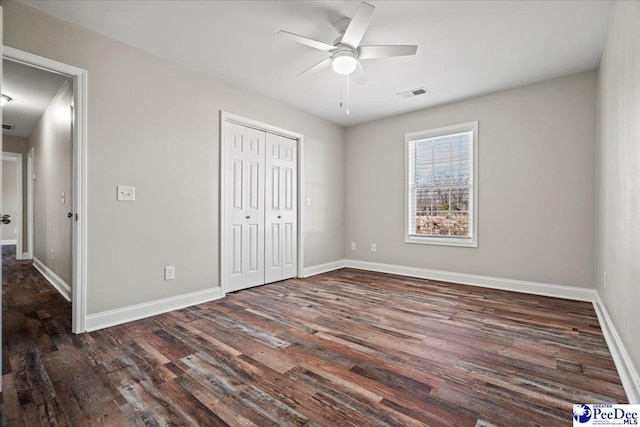 unfurnished bedroom featuring dark wood-style flooring, a ceiling fan, visible vents, baseboards, and a closet