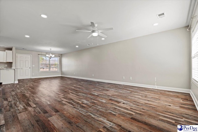 unfurnished living room featuring recessed lighting, ceiling fan with notable chandelier, dark wood-style flooring, visible vents, and baseboards