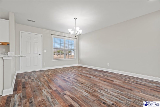 unfurnished dining area featuring baseboards, visible vents, a chandelier, and dark wood-type flooring