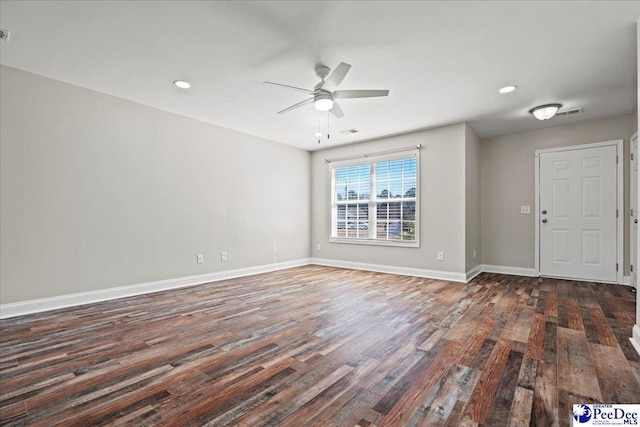 spare room featuring ceiling fan, dark wood-style flooring, visible vents, and baseboards