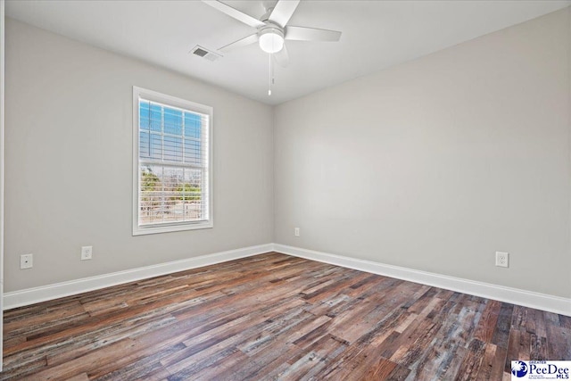 spare room with dark wood-style floors, a ceiling fan, visible vents, and baseboards