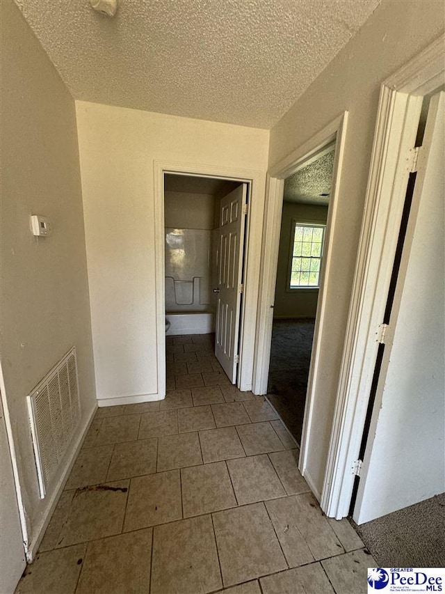 hall with light tile patterned floors and a textured ceiling