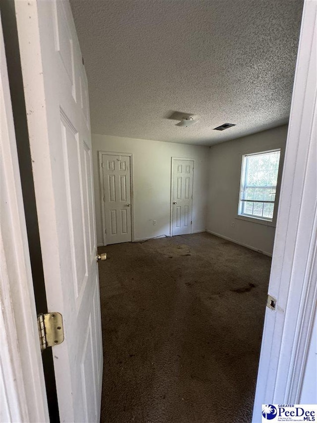 unfurnished bedroom with a textured ceiling and carpet flooring