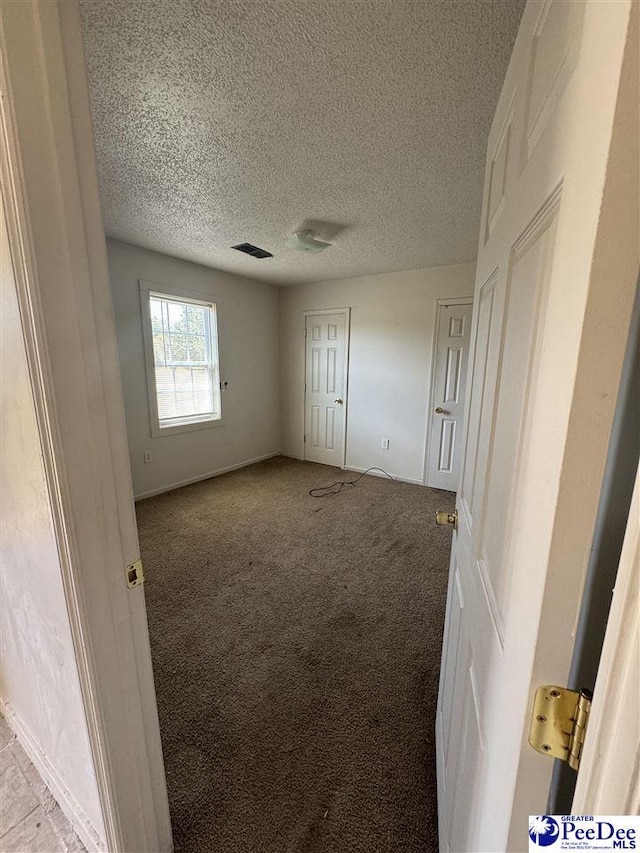 unfurnished bedroom featuring light carpet and a textured ceiling