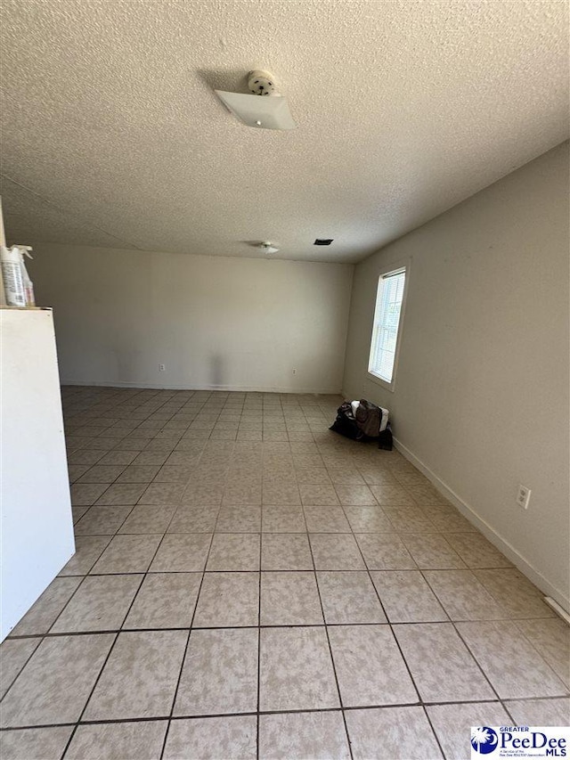 tiled spare room with a textured ceiling