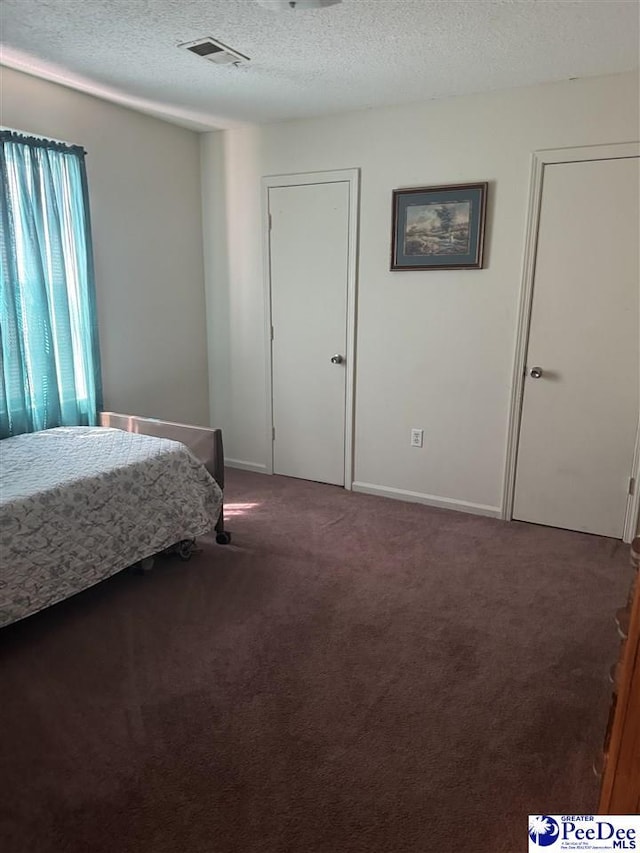 bedroom with a textured ceiling and dark colored carpet