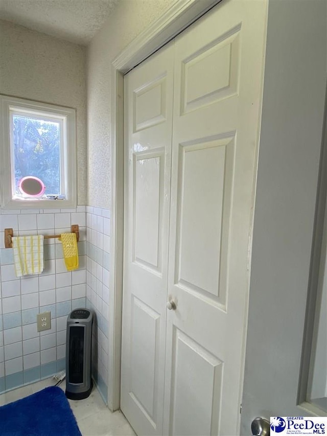 bathroom with tile walls and a textured ceiling