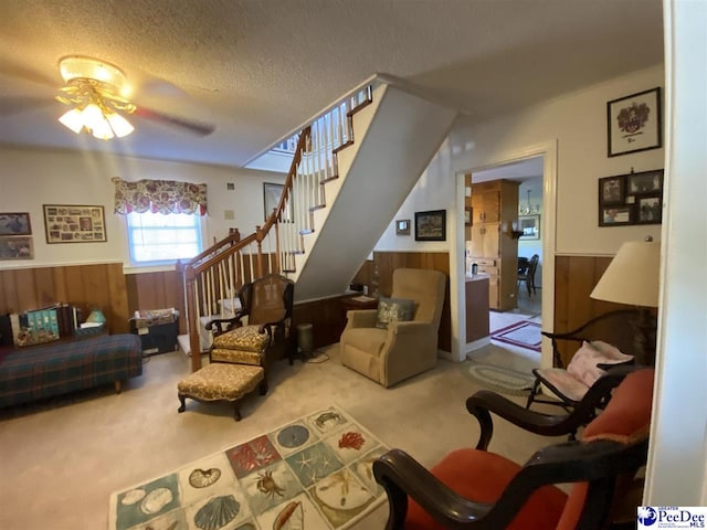 living room with ceiling fan, carpet floors, a textured ceiling, and wood walls