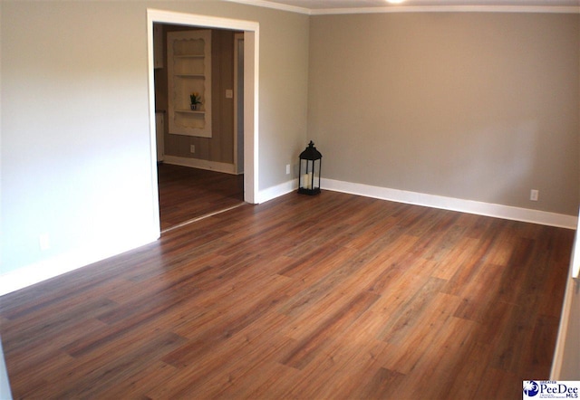 empty room with baseboards, ornamental molding, and dark wood-type flooring
