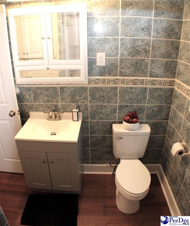 bathroom with tile walls, toilet, and wood finished floors