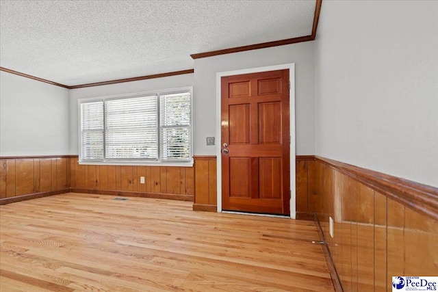 foyer featuring a textured ceiling, wooden walls, and wainscoting