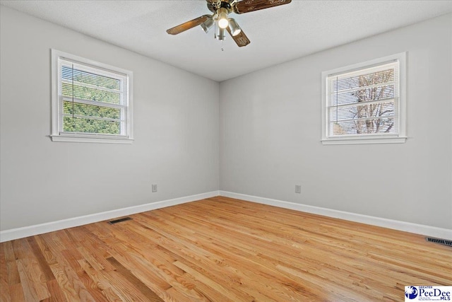 unfurnished room featuring ceiling fan, baseboards, visible vents, and light wood-type flooring