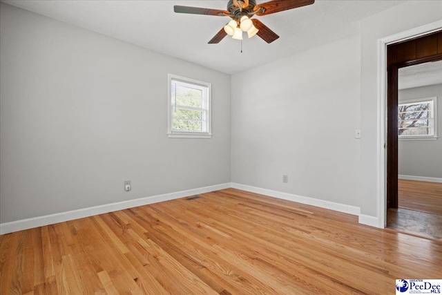 empty room featuring visible vents, baseboards, a ceiling fan, and light wood finished floors