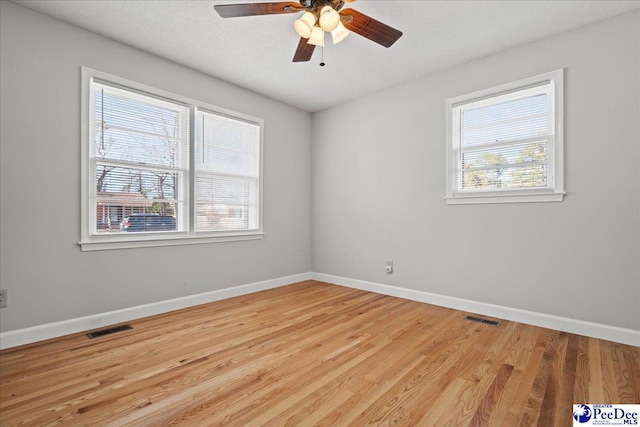 unfurnished room featuring wood finished floors, baseboards, and visible vents