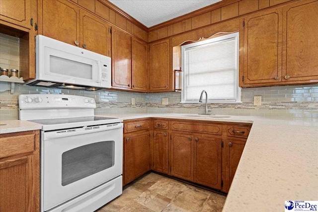 kitchen featuring backsplash, white appliances, light countertops, and a sink