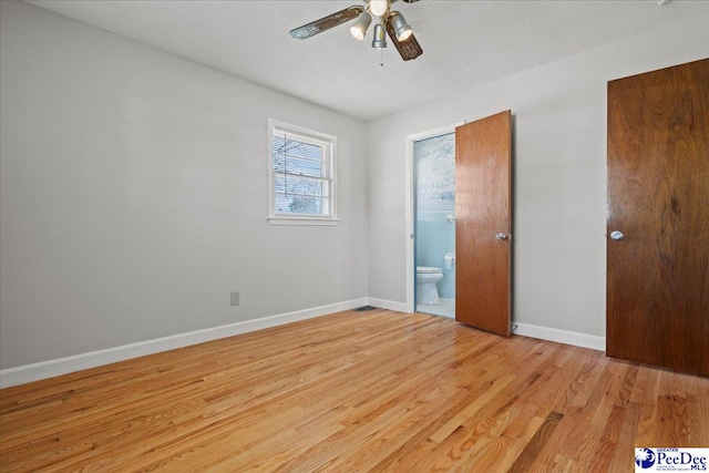 unfurnished bedroom featuring a textured ceiling, ensuite bath, light wood-style floors, baseboards, and ceiling fan