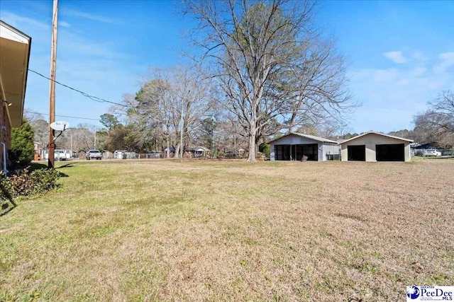 view of yard featuring an outdoor structure, a garage, and a pole building