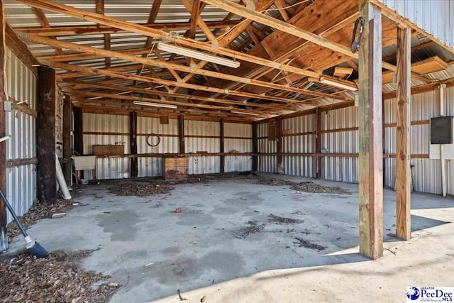 misc room with metal wall, concrete flooring, and lofted ceiling