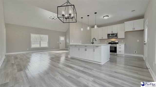 kitchen with appliances with stainless steel finishes, decorative light fixtures, a center island with sink, and white cabinets