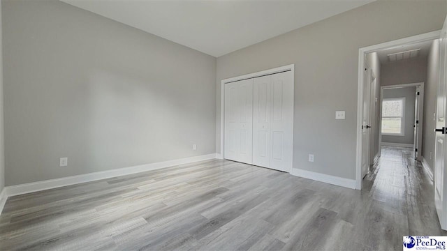 unfurnished bedroom with a closet and light wood-type flooring