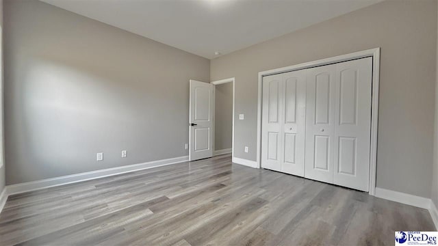 unfurnished bedroom with a closet and light wood-type flooring