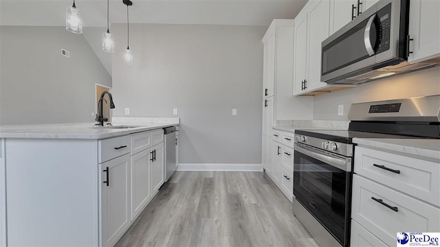 kitchen featuring sink, appliances with stainless steel finishes, pendant lighting, light hardwood / wood-style floors, and white cabinets