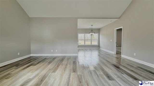 empty room featuring an inviting chandelier and light wood-type flooring