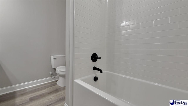 bathroom with hardwood / wood-style flooring, tiled shower / bath combo, and toilet