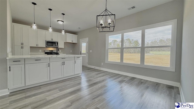 kitchen featuring stainless steel appliances, white cabinets, light hardwood / wood-style floors, and decorative light fixtures