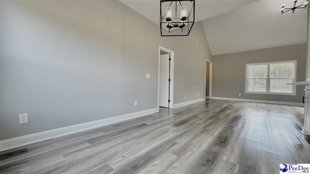 unfurnished living room featuring high vaulted ceiling, a notable chandelier, and light wood-type flooring