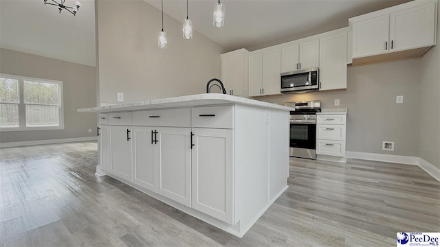 kitchen featuring pendant lighting, appliances with stainless steel finishes, a center island with sink, and white cabinets