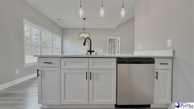 kitchen featuring white cabinetry, sink, stainless steel dishwasher, and decorative light fixtures