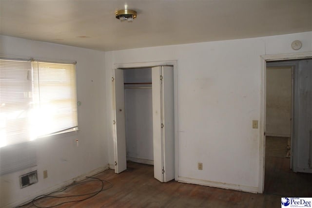 unfurnished bedroom with dark hardwood / wood-style flooring and a closet