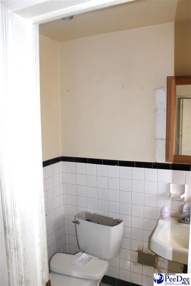 bathroom featuring toilet, sink, and tile walls